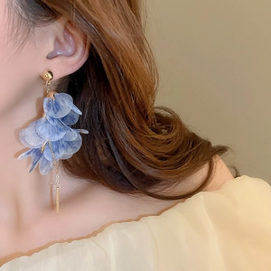 Close-up of elegant blue fabric flower tassel earrings worn on a model in soft light