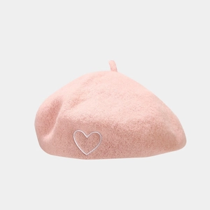 Close-up of pink wool beret featuring white heart embroidery and top stalk detail