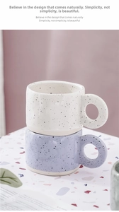 Close-up of minimalist hand-pinched ceramic mugs with black ink splatter and large ring handles
