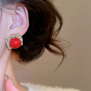 Close-up of red gemstone earrings with intricate gold filigree and pavé zircon details