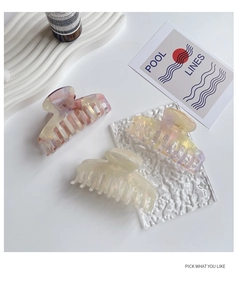 Three acetate hair claws in colorful marble and gradient finishes on a white tray