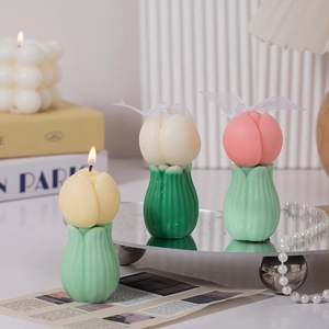 Tres velas con forma de tulipán en amarillo, blanco y rosa sobre bandeja de espejo