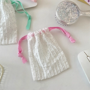 Detail of white cotton drawstring pouch with black polka dots and colorful ribbons