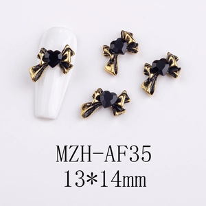 Macro shot of 13x14mm gold bow and black heart alloy nail art charms on white nail