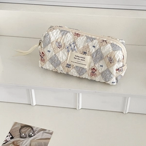Detail of quilted teddy bear makeup bag with blue plaid patterns and side webbing