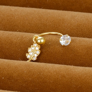 Macro shot of gold leaf pendant belly piercing with white zircon on velvet display