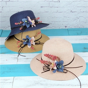 Dettaglio di cappelli di paglia intrecciata con fiori di stoffa e bacche decorativi