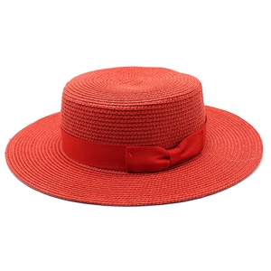 Close-up of bright red boater hat with fine straw weave and elegant ribbon bow detail