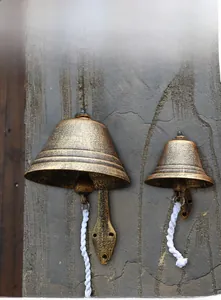 Detail of two vintage cast iron doorbells in bronze finish with white pull ropes