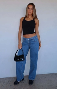 Detail of high-waist straight-leg blue washed jeans paired with a black ribbed tank top