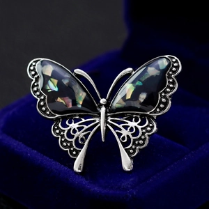 Elegant silver butterfly brooch with iridescent shell wings on dark velvet background