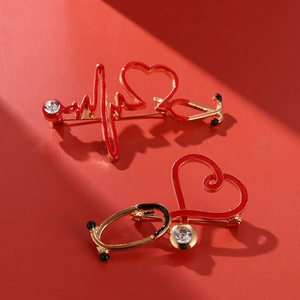 Close-up of golden medical stethoscope brooch with red enamel and crystal detail
