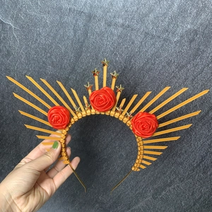 Detail of golden sunburst crown featuring red fabric roses and small gold star ornaments