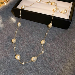 Close-up of gold-plated chain and white baroque pearls on a soft plush background