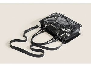 Detail of gothic ita bag with spider web pattern, butterfly accents and metal chain straps