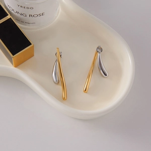 Boucles d'oreilles géométriques minimalistes en or et argent sur plateau en céramique