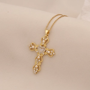 Macro shot of gold cross pendant with pearls, small crystals and a center heart