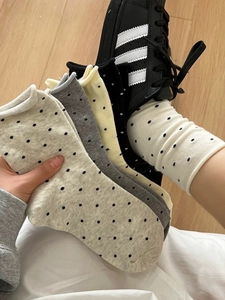Détail de chaussettes à pois crème, gris et jaune avec poignets roulés minimalistes