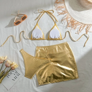 Flat lay of metallic gold three-piece bikini set with removable pads and matching skirt
