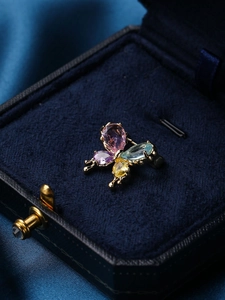 Close-up of butterfly brooch with colorful gemstones in a blue velvet gift box