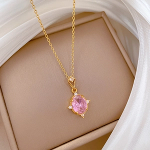 Luxurious gold necklace featuring a pink oval gemstone pendant on beige jewelry box