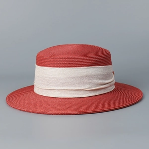 Detail of terracotta flat top straw hat with cream fabric band and fine woven texture