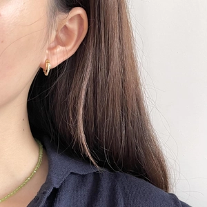 Gold hoop earrings with zircon stones paired with a green beaded necklace on a model