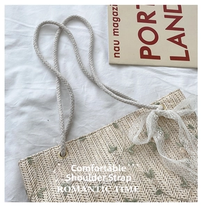 Detail of straw tote bag with green floral embroidery and white lace bow decoration