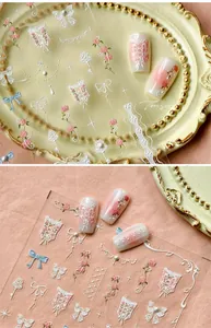 Macro shot of 3D embossed lace nail stickers with pink roses and ribbon textures