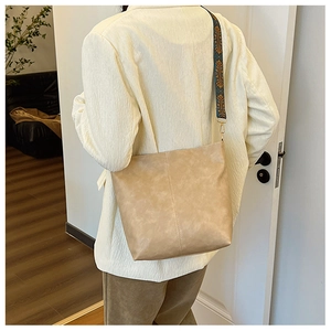 Detail view of beige PU leather tote bag featuring a colorful ethnic embroidery strap