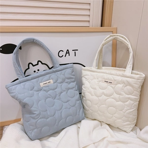 Close-up of quilted floral pattern tote bags in light blue and beige with simple wish labels