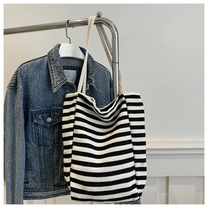 Close-up of black and white striped canvas tote bag with thick cream shoulder straps