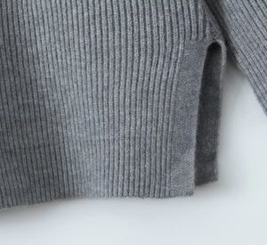 Close-up of grey knit sweater detail with vertical texture and side split hem design