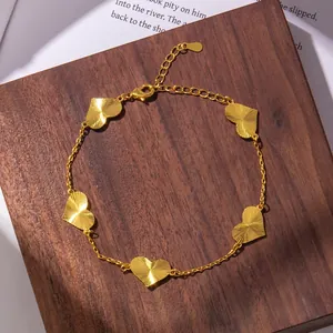 Detail of gold bracelet featuring heart charms with radial texture on a wooden stand