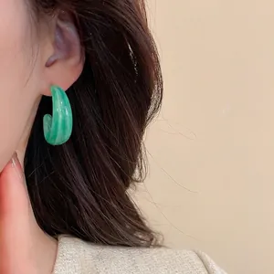 Boucles d'oreilles minimalistes en acrylique vert clair en forme de C sur un mannequin