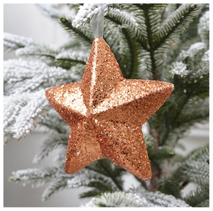 Sparkling champagne gold star ornament with sequins hanging on a snowy Christmas tree branch
