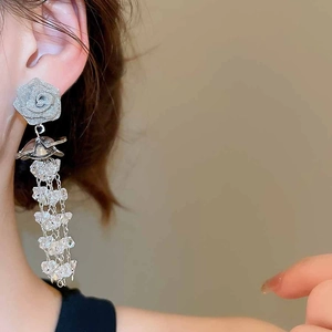 Close-up of silver rose stud earrings featuring sparkling crystal fringe tassels on model