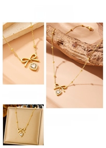 Détail du collier à billes dorées avec nœud et pendentif cœur serti de zircone