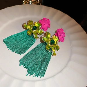 Détail d'une boucle d'oreille fleur rose avec franges vertes et pierre incrustée