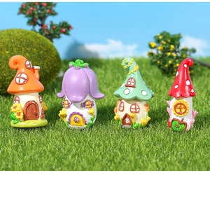 Detail of four miniature fairy resin houses with mushrooms on green faux grass