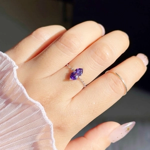 Detail of silver chain ring with double purple heart gemstones worn on a finger