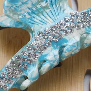 Macro shot of blue marble acetate hair claw with sparkling rhinestones and smooth teeth