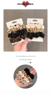 Detail of satin hair scrunchies in assorted warm tones with glossy fabric texture