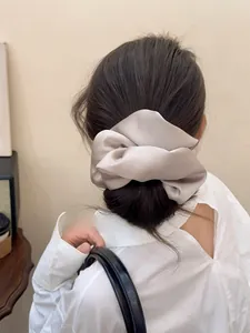 Close-up of oversized champagne satin scrunchie showing silky texture and pleated volume