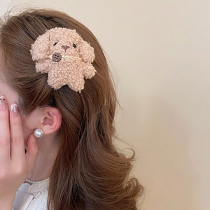 Detailed view of a curly beige plush dog hair clip with a brown button on female hair