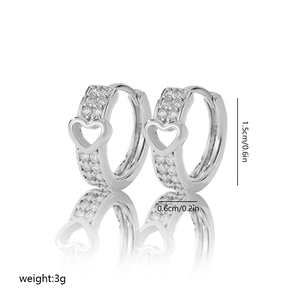 Detail of silver hoop earrings with hollow heart design and cubic zirconia inlay