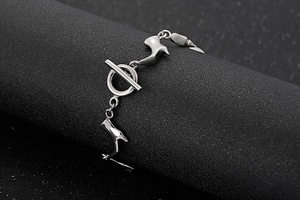 Détail de bracelet en acier titane avec breloques de bottes et fermoir à bascule