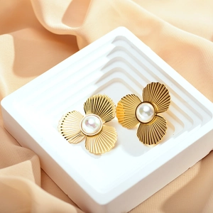 Close-up of golden petal earrings with pearl center and textured radial engravings