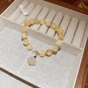 Beaded bracelet with yellow gemstones, pearl accents, and white lotus flower pendant