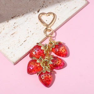 Close-up of red strawberry pendants with gold leaves and heart-shaped keyring clasp